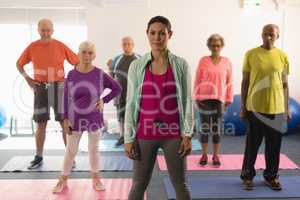 Front view of female trainer and senior people looking at camera