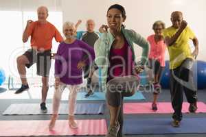 Front view of female trainer assisting senior people in fitness studio