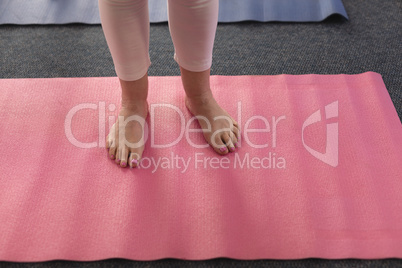 Low section of woman standing on exercise mat
