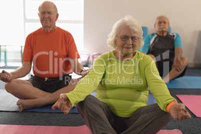 Senior people doing yoga in fitness studio