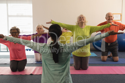 Female trainer assisting senior people in fitness studio