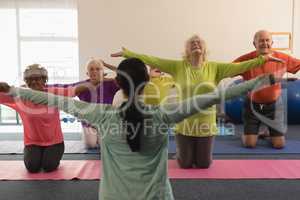 Female trainer assisting senior people in fitness studio