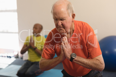 Senior man doing yoga in fitness studio