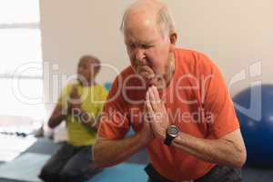 Senior man doing yoga in fitness studio