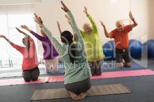 Young female trainer assisting senior people in fitness studio