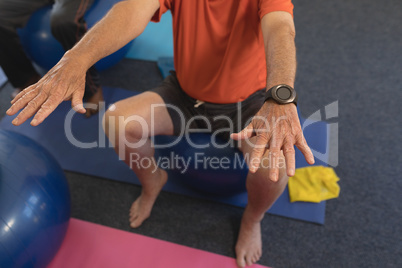 Senior man exercising on exercise ball in fitness studio