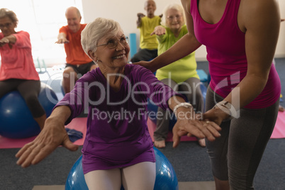 Female trainer assisting senior woman in fitness studio