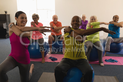 Front view of senior people exercising with female trainer