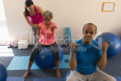 Female trainer assisting senior woman in fitness studio