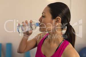 Side view of beautiful young woman drinking water after workout
