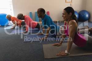 Side view of young female trainer exercising with senior people