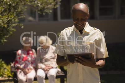 Front view of senior man suing digital tablet in garden