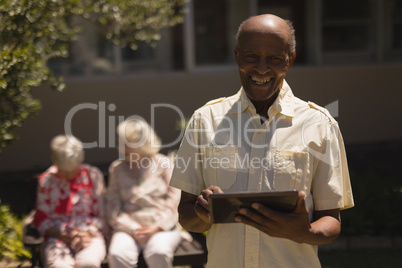 Front view of senior man with digital tablet looking at camera in garden