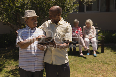 Front view of senior friends discussing over digital tablet