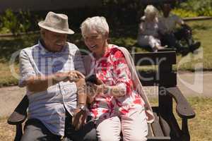 Front view of senior couple discussing over mobile phone in garden