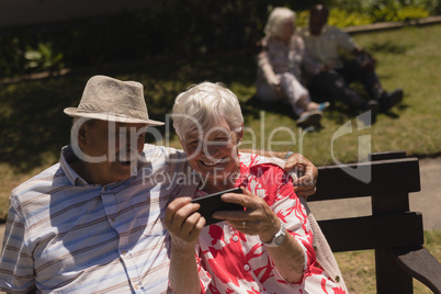 Front view of senior couple using mobile phone in garden