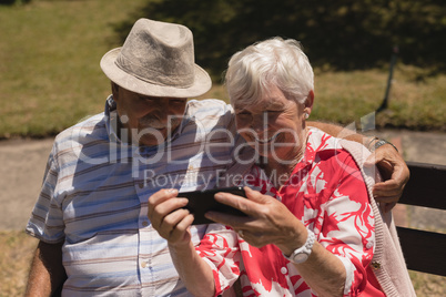 Front view of senior couple using mobile phone in garden