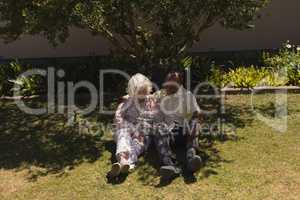 Front view of senior couple using mobile phone in garden
