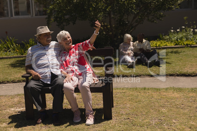 Front view of senior couple taking selfie with mobile phone in garden