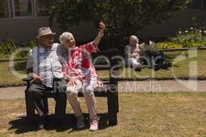 Front view of senior couple taking selfie with mobile phone in garden