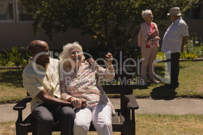 Front view of senior couple taking selfie with mobile phone in garden