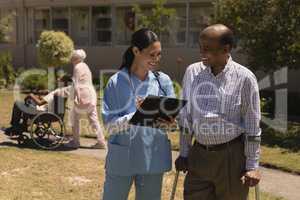 Front view of young female doctor discussing medical report with senior man on clipboard