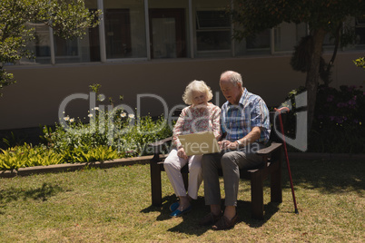 Front view of senior couple using laptop in garden