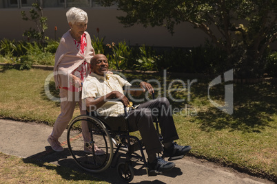 Front view of senior woman pushing senior man in a wheelchair