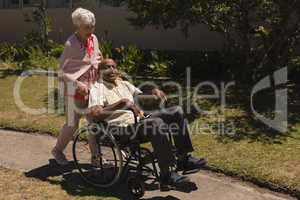 Front view of senior woman pushing senior man in a wheelchair