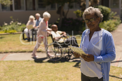 Front view of senior woman with digital tablet looking at camera in garden