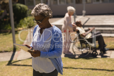 Front view of senior woman using digital tablet in garden