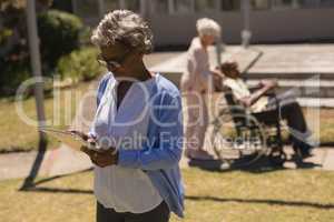 Front view of senior woman using digital tablet in garden