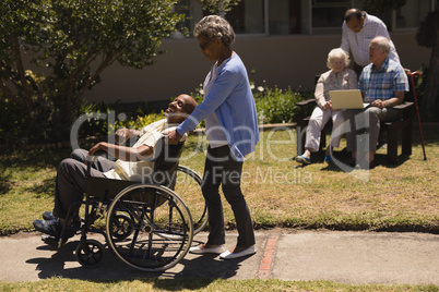Front view of senior woman pushing senior man in a wheelchair