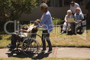 Front view of senior woman pushing senior man in a wheelchair