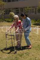 Young female doctor helping disabled senior woman in garden