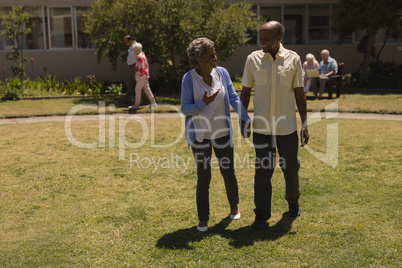 Front view of senior couple holding hands and interacting with each other in garden