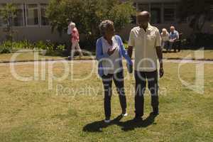 Front view of senior couple holding hands and interacting with each other in garden