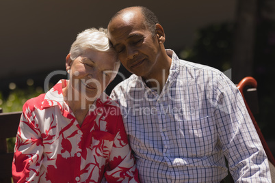 Front view of senior couple head to head with eyes closed in garden
