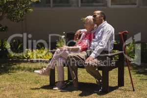 Side view of senior couple relaxing on bench in garden