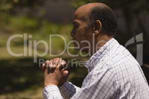 Side view of senior man hands leaning on a cane while sitting on bench