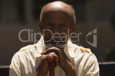 Front view of senior man hands leaning on a cane while sitting on bench