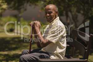 Side view of senior man hands leaning on a cane while sitting on bench