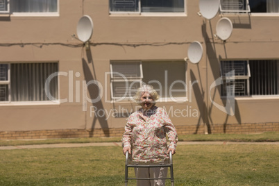 disabled senior woman walking with walker in garden