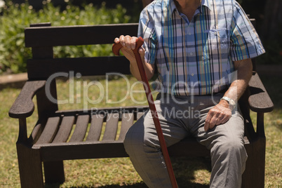 senior man sitting with cane on bench