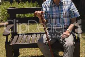 senior man sitting with cane on bench