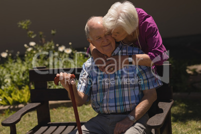 senior woman embracing and kissing senior man in garden