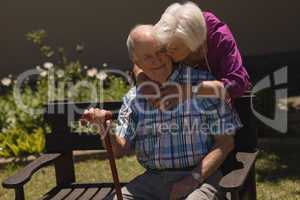 senior woman embracing and kissing senior man in garden