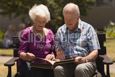 Senior couple looking at photo album in the park