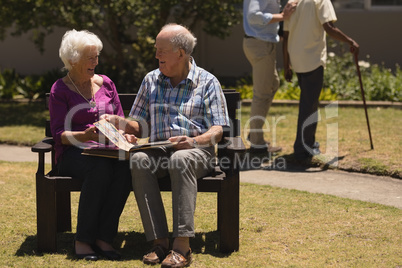 Senior couple looking at photo album in the park