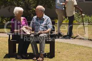 Senior couple looking at photo album in the park